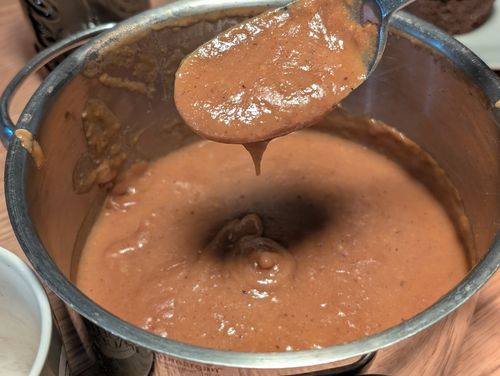 Ein Metalltopf aus dem Bratensoße gelöffelt wird