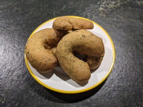 Ein paar braune Kipferl auf einer Untertasse mit gelbem Rand auf einer Steinplatte