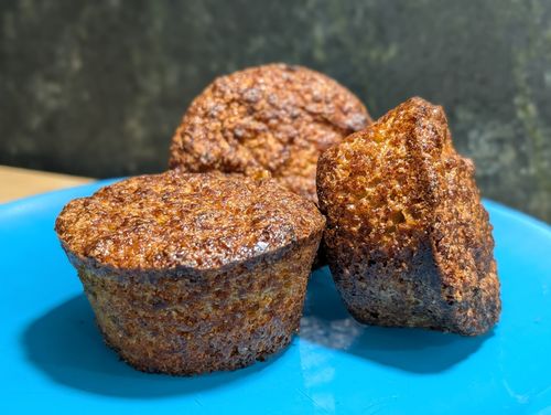 Drei dunkle Muffins auf einem blauen Teller
